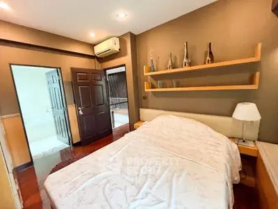 Cozy bedroom with elegant decor and wooden flooring, featuring a comfortable bed and stylish wall shelves.