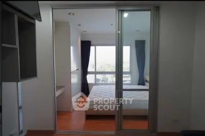 Modern bedroom with large window and sliding glass door, featuring a minimalist design and ample natural light.