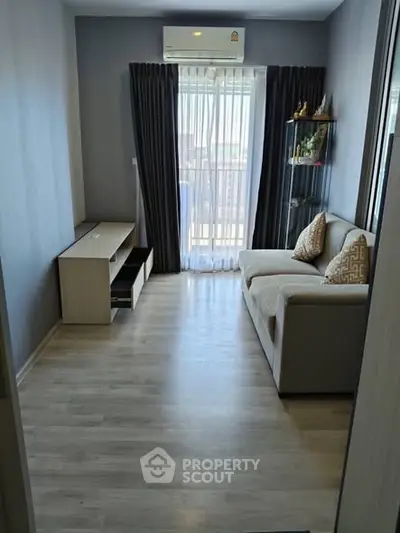 Cozy living room with modern sofa and natural light from large window.