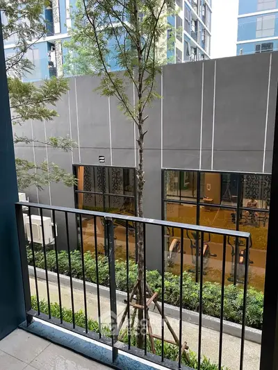 Modern apartment balcony with garden view and sleek building exterior.