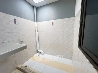 Spacious bathroom with modern tiles and natural light from skylight