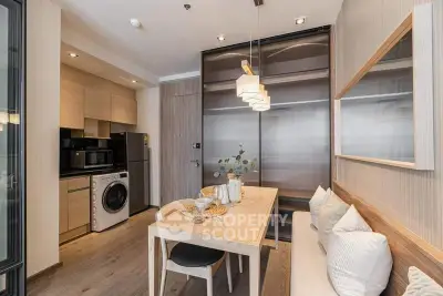 Modern kitchen with dining area, featuring sleek appliances and stylish lighting in a cozy apartment.
