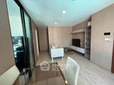 Modern living room with sleek furniture and open layout, featuring a cozy sofa and flat-screen TV.