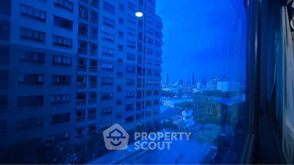 Stunning cityscape view from high-rise apartment window overlooking pool and skyline.