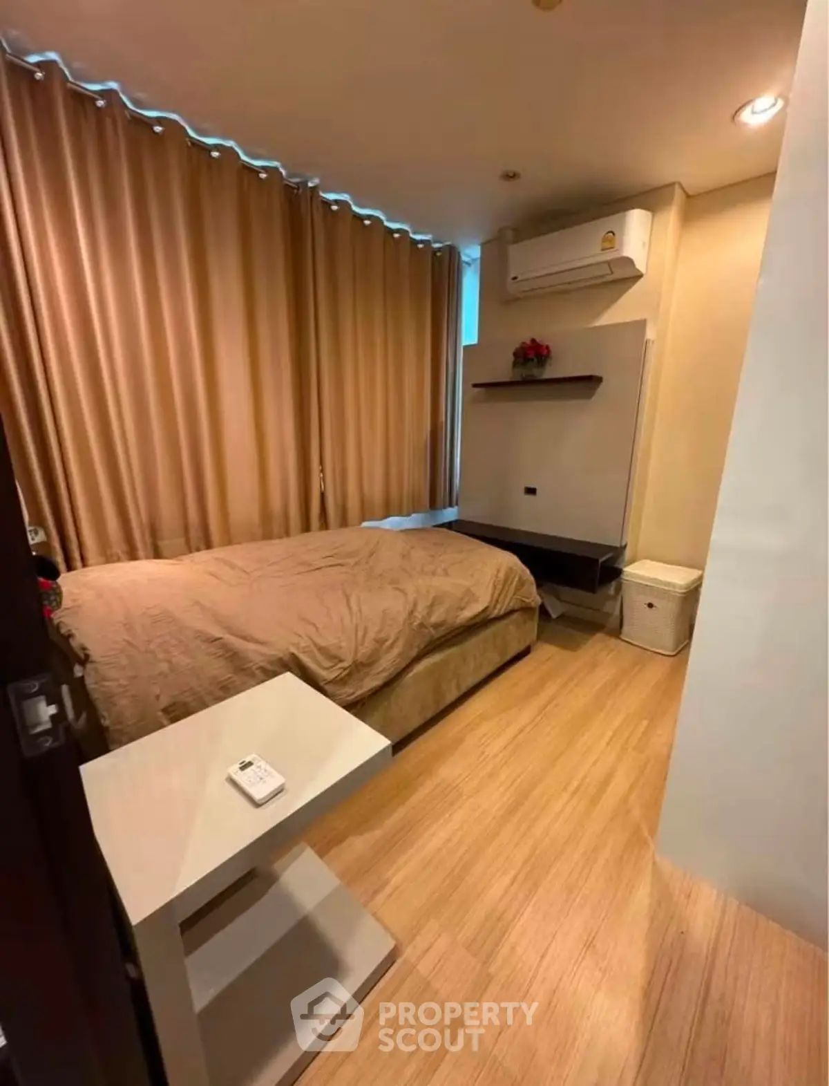 Cozy bedroom with modern air conditioning and elegant wooden flooring, perfect for a comfortable living experience.