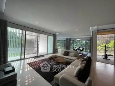Spacious modern living room with large windows and garden view, perfect for relaxation.