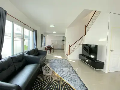 Spacious modern living room with sleek black sofa and open kitchen layout