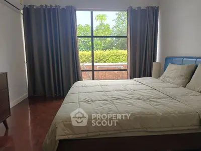 Spacious bedroom with large window and garden view, featuring elegant curtains and cozy bedding.