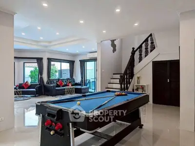 Spacious living room with pool table and elegant staircase in modern home