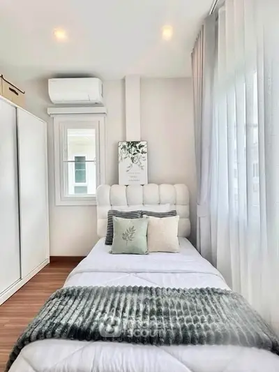 Cozy bedroom with modern decor, featuring a single bed, plush pillows, and ample natural light.