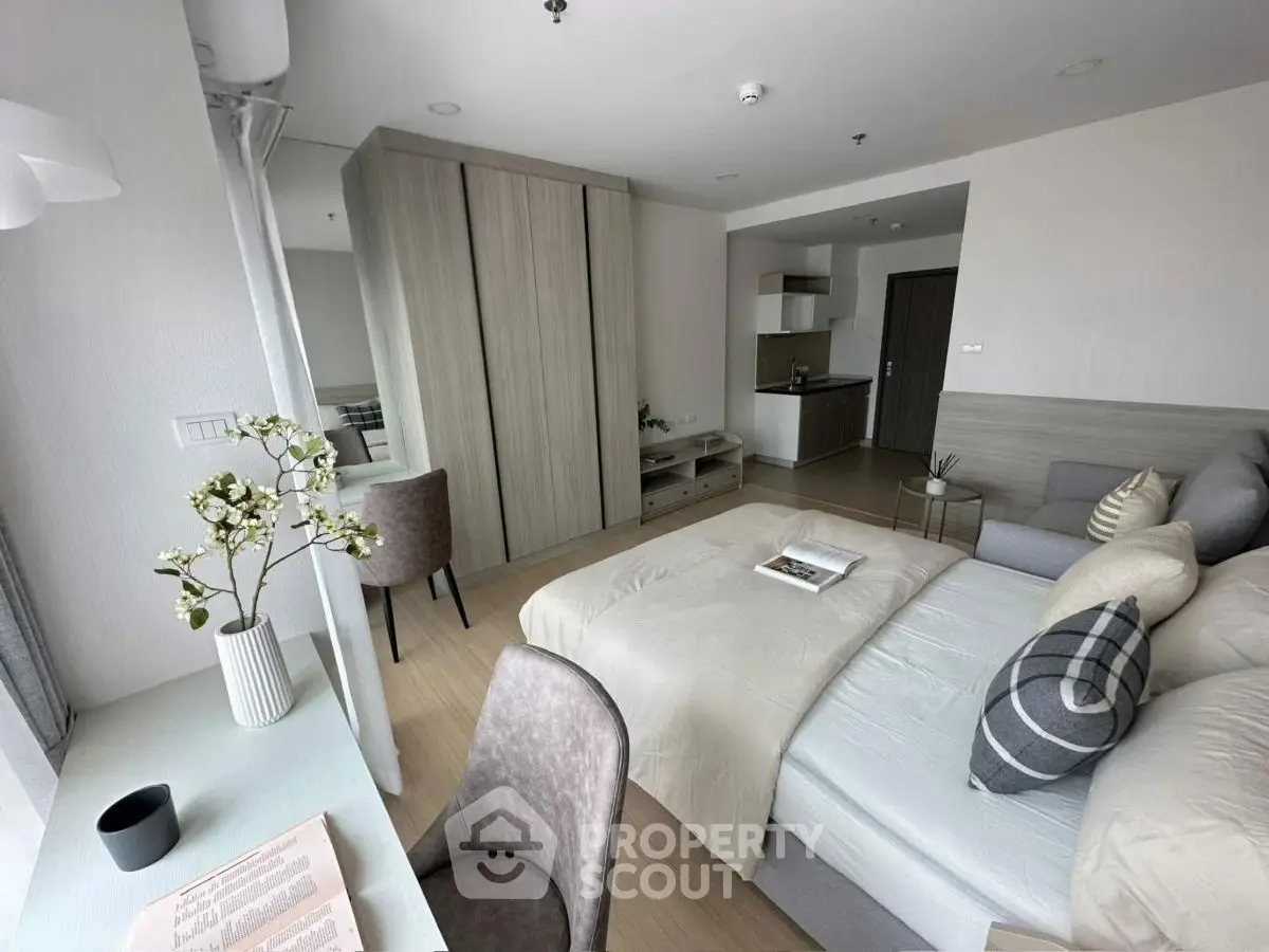 Modern studio apartment with cozy bedroom and compact kitchen area, featuring stylish decor and natural light.