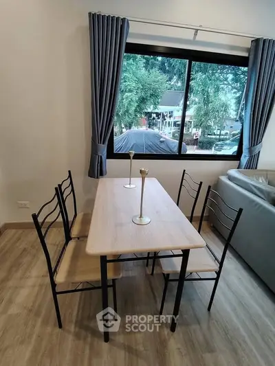 Modern dining area with stylish table and chairs, large window view, and elegant curtains.