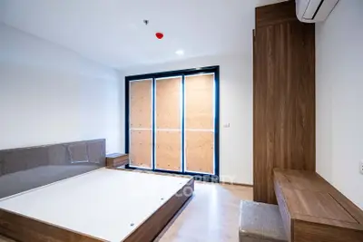 Spacious modern bedroom with sleek wooden furniture and large windows.
