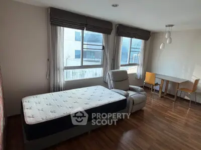 Spacious bedroom with large windows and modern furnishings in a stylish apartment.