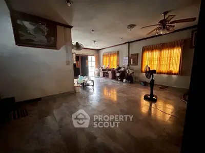 Spacious living room with ceiling fans and large windows, perfect for family gatherings.