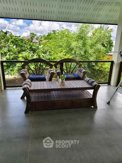 Spacious balcony with rustic wooden furniture and lush green views, perfect for relaxation.