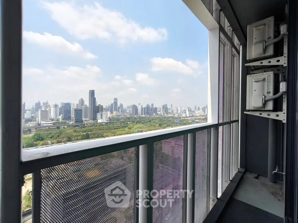 Stunning cityscape view from a high-rise balcony with modern railing and clear blue sky.