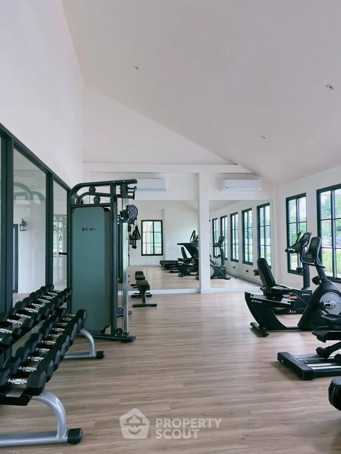Spacious modern gym with state-of-the-art equipment and large windows for natural light.