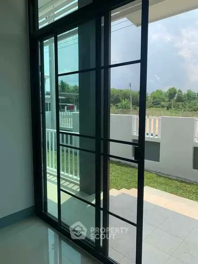 Modern sliding glass door leading to a spacious balcony with a serene garden view.