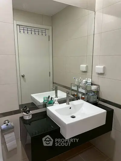 Modern bathroom with sleek sink and mirror, featuring organized toiletries.