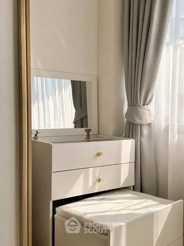 Elegant bedroom corner with vanity and soft natural light through curtains.