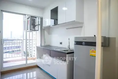 Modern kitchen with sleek cabinets and balcony view in urban apartment