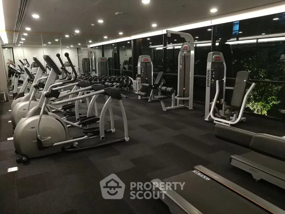 Modern gym with state-of-the-art fitness equipment and large mirrors in a residential building.