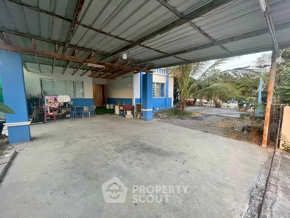 Spacious covered parking area with blue accents and tropical surroundings