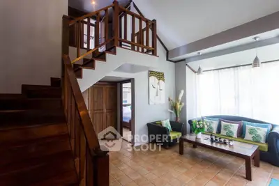 Charming living room with wooden staircase and cozy seating area, perfect for relaxation.