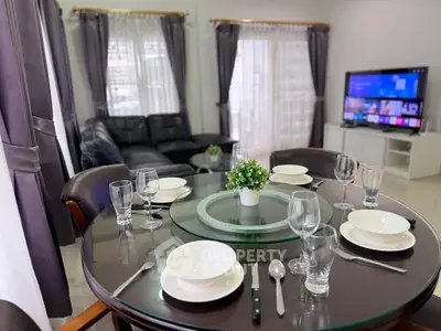 Elegant living room with dining area, featuring a cozy sofa and modern entertainment setup.