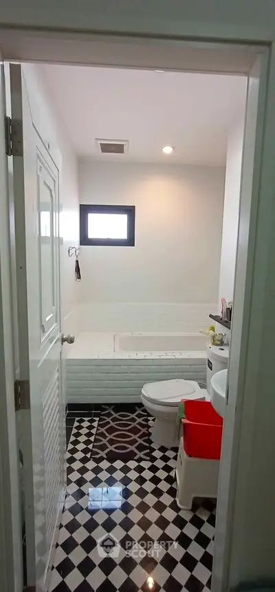 Charming bathroom with stylish black and white checkered floor and a cozy bathtub.
