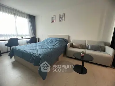 Modern bedroom with stylish decor, featuring a cozy bed, elegant sofa, and natural light from large window.