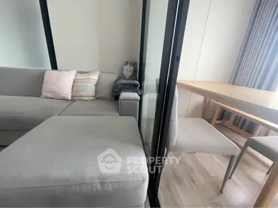 Modern living room with cozy gray sofa and dining area, featuring elegant decor and natural light.