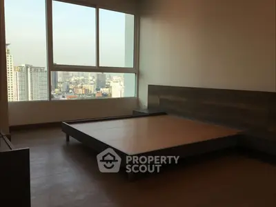 Spacious bedroom with large window offering stunning city views in modern apartment.