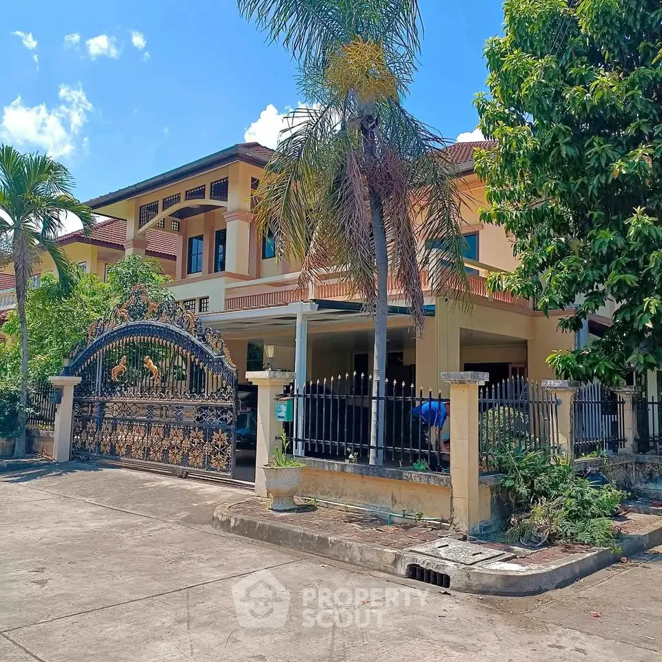 Stunning two-story villa with ornate gate and lush greenery, perfect for luxurious living.