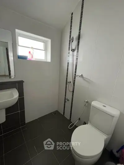 Modern bathroom with sleek design and contemporary fixtures, featuring a shower and toilet.