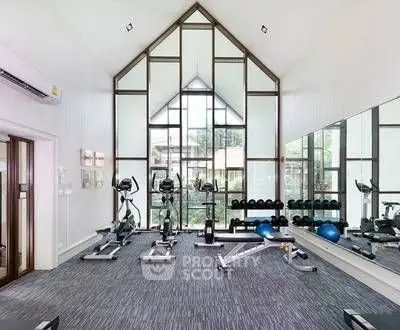 Modern gym with large windows and fitness equipment in a stylish real estate property.