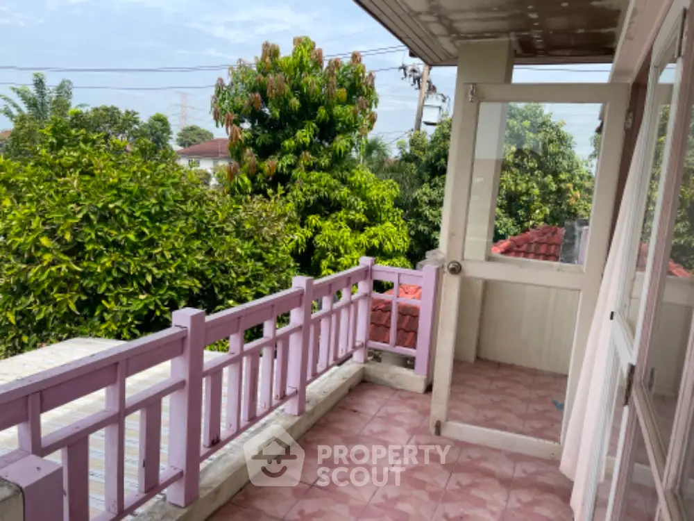 Spacious balcony with pink railings offering a serene view of lush greenery, perfect for outdoor relaxation and entertainment.