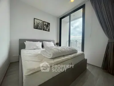 Modern bedroom with large window and city view, featuring a cozy bed and stylish decor.