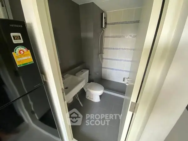 Compact modern bathroom with sleek fixtures and a shower area in a stylish apartment.