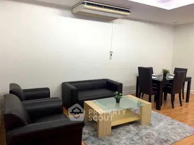 Modern living room with sleek black furniture and elegant dining area.