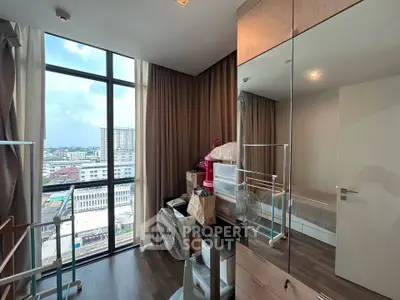 Modern bedroom with floor-to-ceiling windows offering stunning city views, featuring sleek furniture and ample storage.