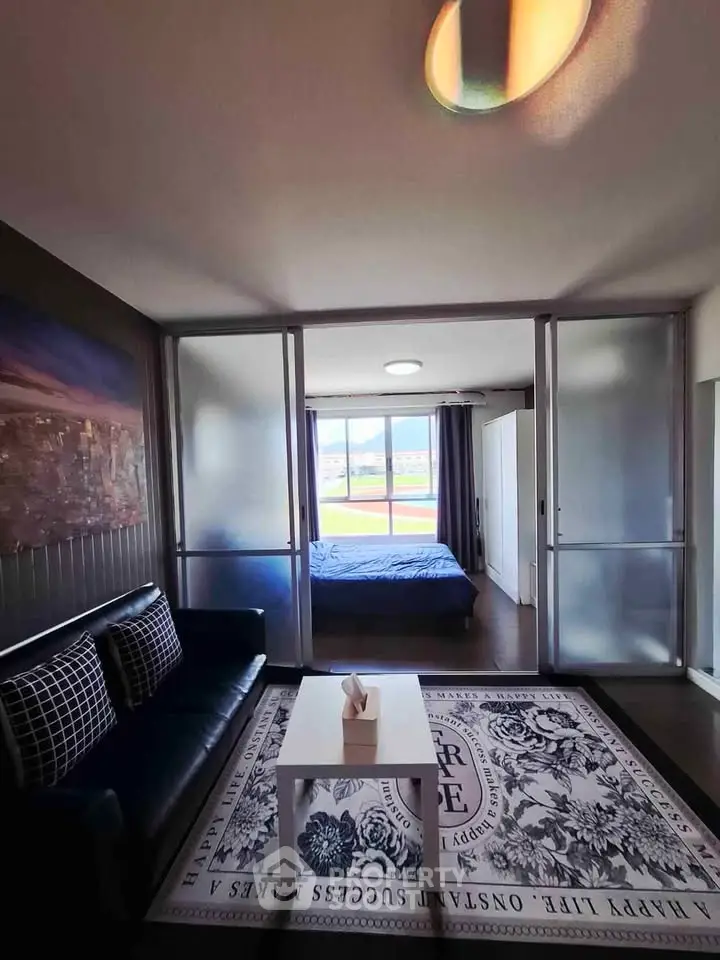 Modern living room with sliding glass doors leading to a bedroom, featuring stylish decor and ample natural light.
