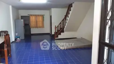 Spacious living area with blue tiled floor and staircase, featuring a fridge and dining set.