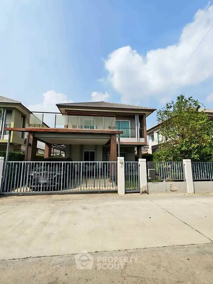 Modern two-story house with spacious driveway and gated entrance in suburban neighborhood.