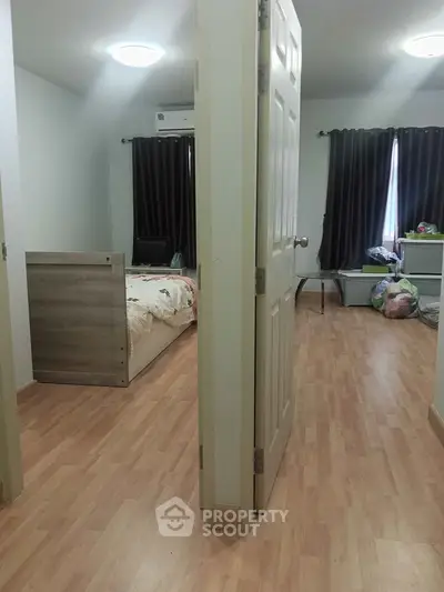 Spacious bedroom with wooden flooring and natural light, featuring a cozy bed and modern decor.