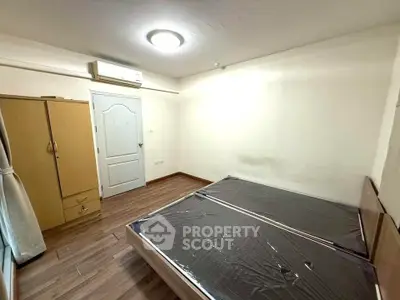 Spacious bedroom with wooden flooring and ample natural light, featuring a wardrobe and air conditioning.