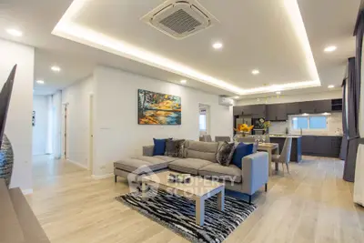 Spacious modern living room with open kitchen, stylish decor, and elegant lighting.