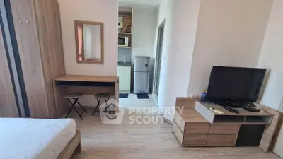 Modern studio apartment with cozy furnishings and compact kitchen area.