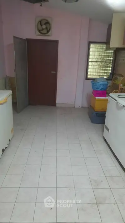 Spacious utility room with tiled floor and storage options.